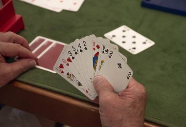 Main d'un joueur tenant des cartes au Bridge